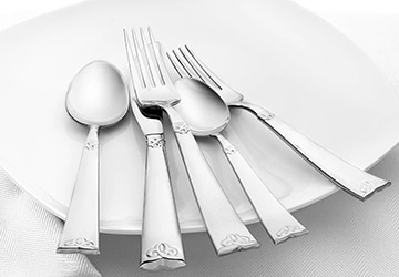 Silver knives, forks, and spoons arranged on a white plate