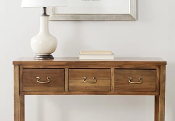 Wooden console table with metal drawer pulls and a table lamp