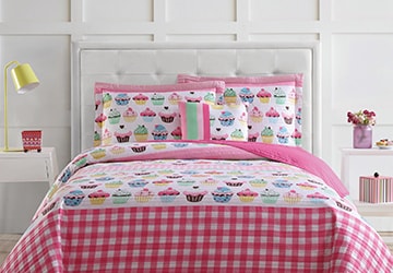 Pink quilt with a cupcake pattern on a child’s bed