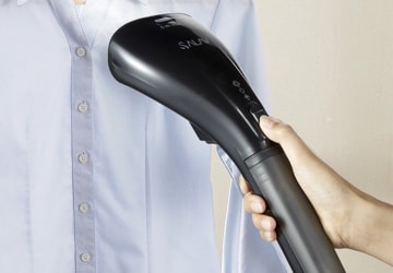 Garment steamer being used on a blue button-up shirt