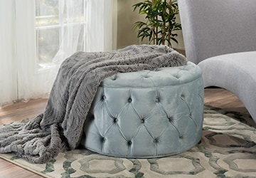 Button-tufted blue ottoman on a geometric rug in a living room