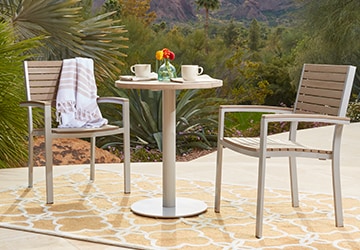 A metal and wood bistro set on a yellow area rug