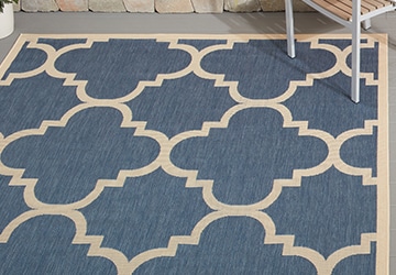 Closeup of a blue outdoor rug with a geometric beige pattern