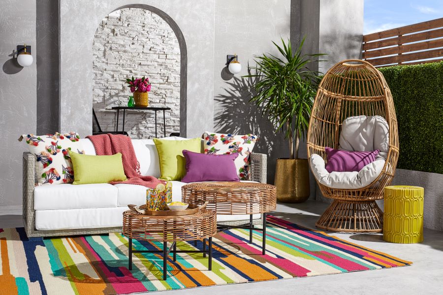 Patio with outdoor loveseat and white cushions, a wicker egg chair, and matching nesting tables