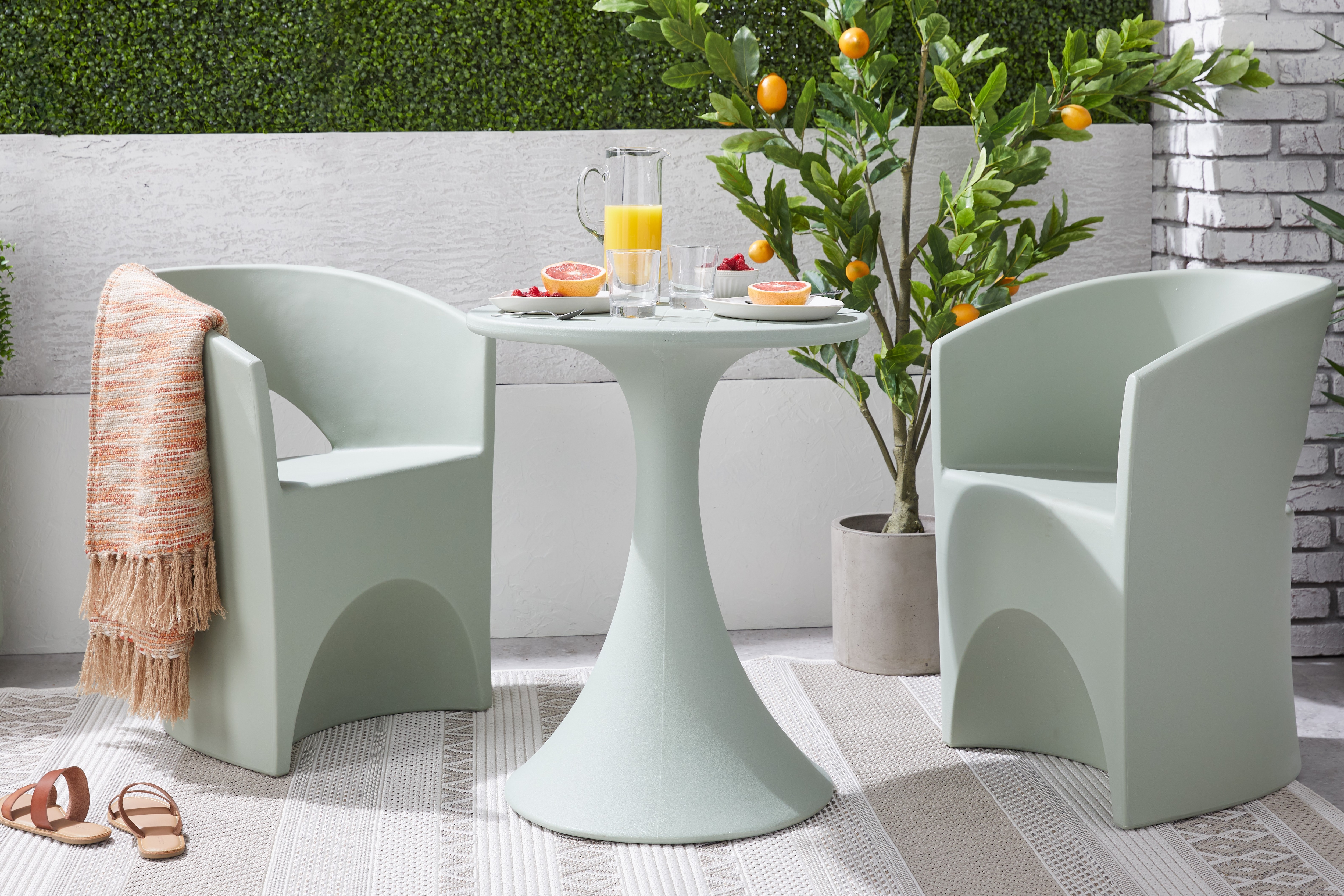 Light blue outdoor dining set with modern barrel chairs and a round pedestal table