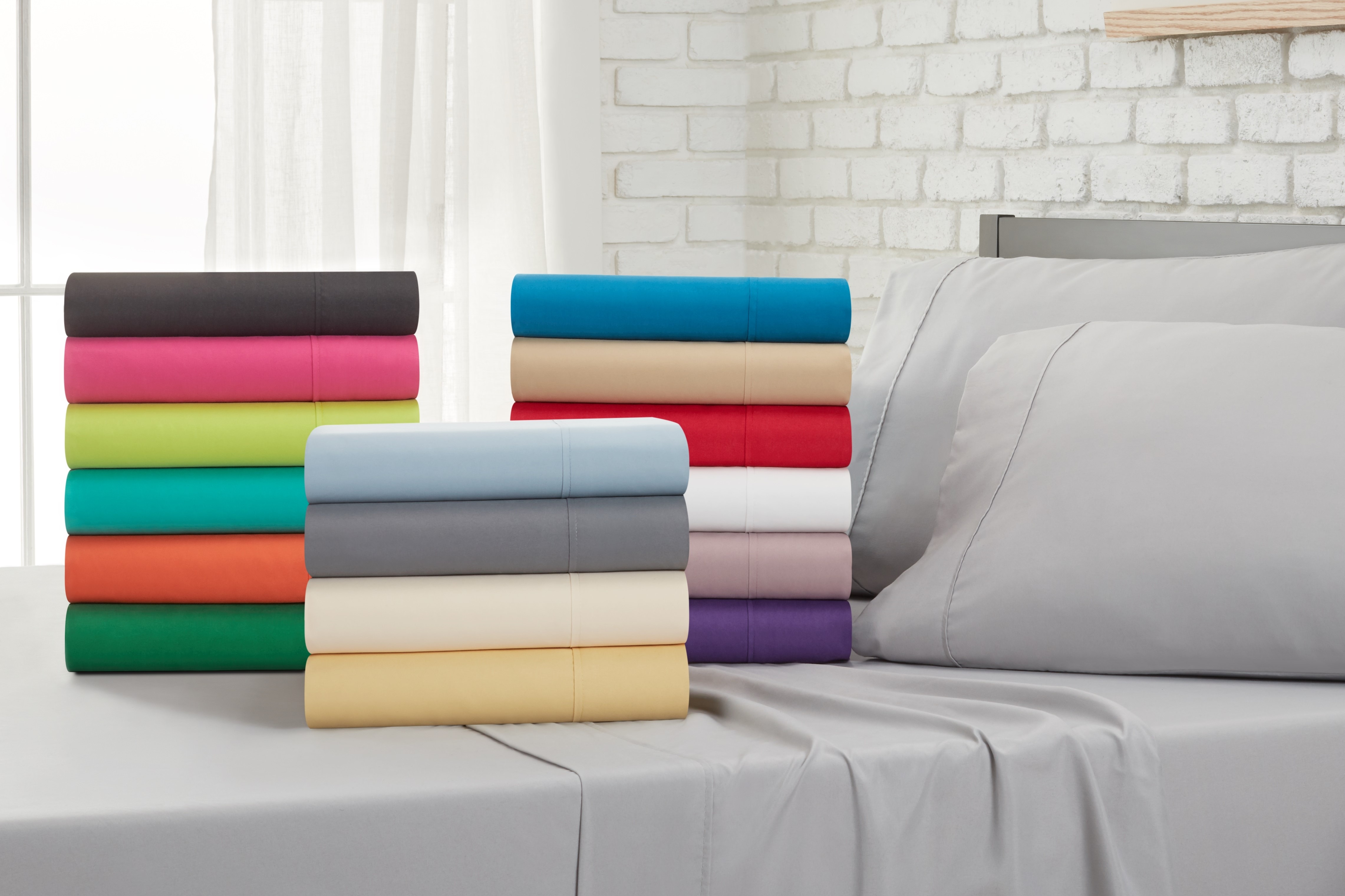 Stack of sheets on a bed with a grey flat sheet